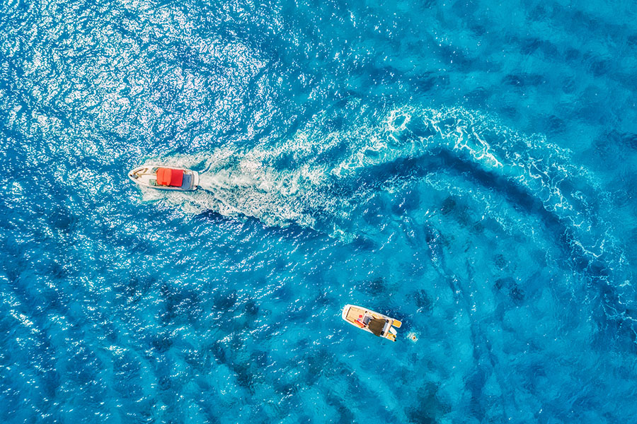 Aerial view of floating motorboat in transparent blue sea
